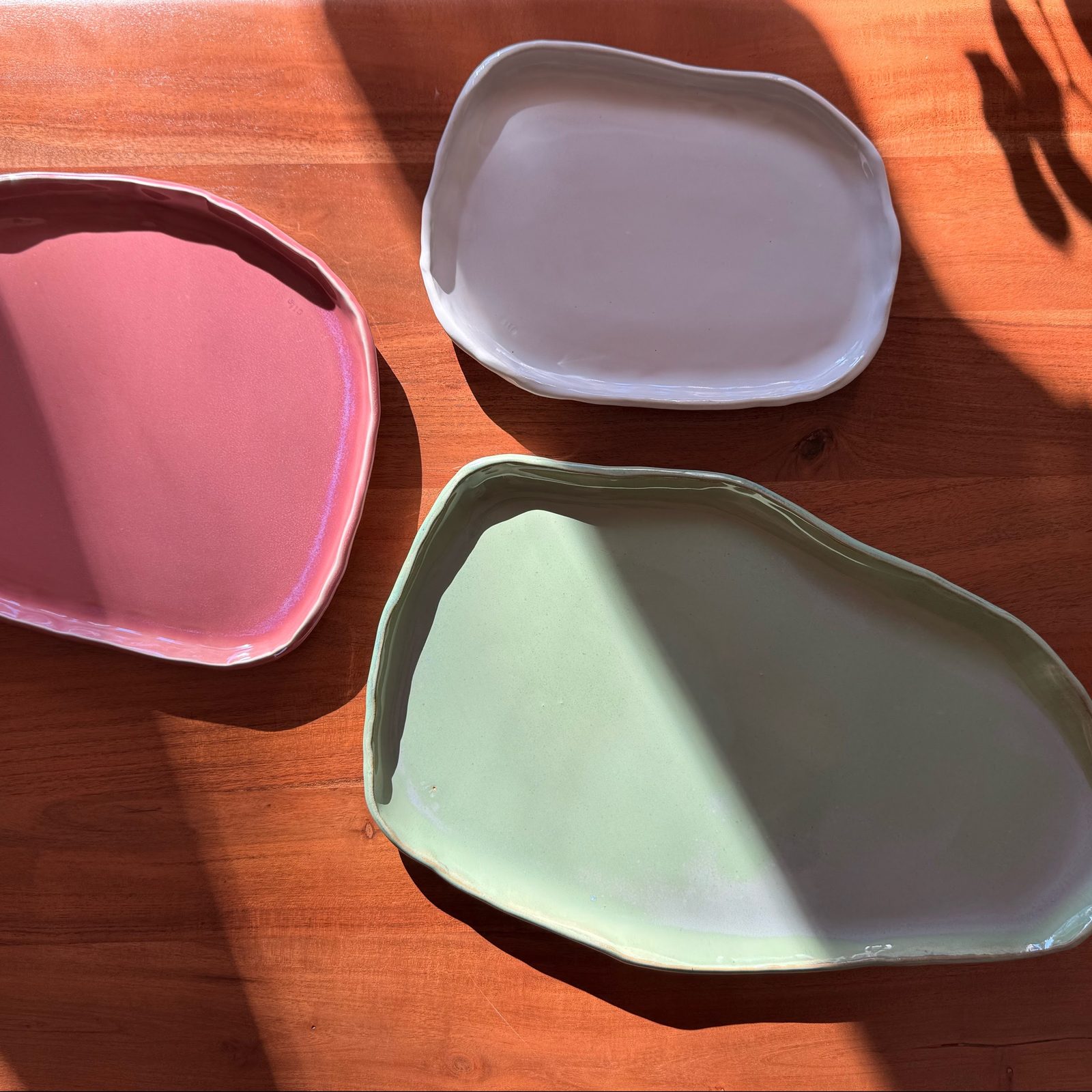 Rose, white and sage platters on a sunlit wooden table
